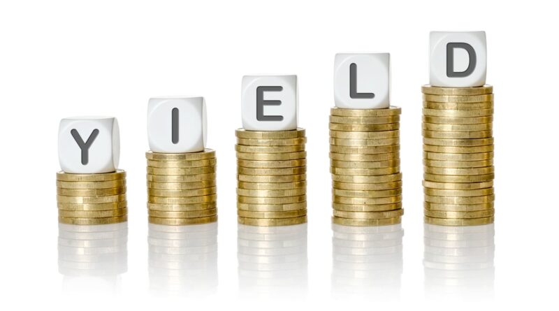 Dice spelling out "yield" on top of coin stacks.