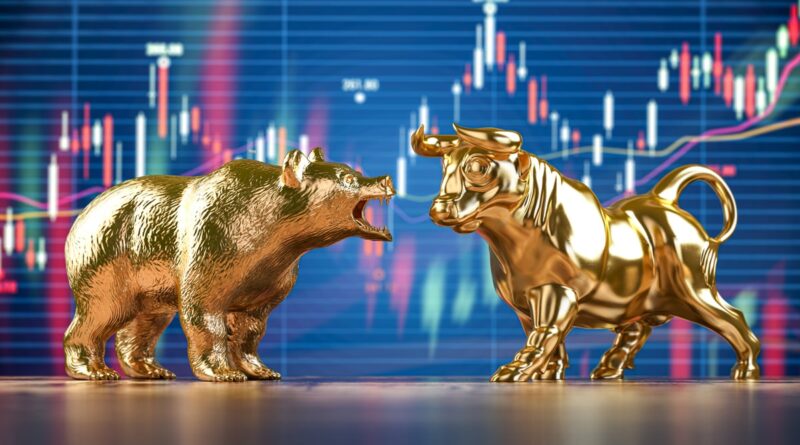 A gold bull and bear facing off in front of a large stock market chart.